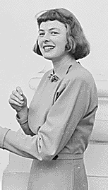 Black and white photograph of a smiling lady with neck-length dark hair in a smart but plain dress with a collar and full length sleeves