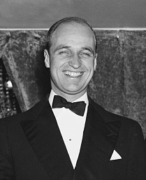 James Roosevelt, wearing a tuxedo and bow tie, smiles at the camera.