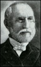 Head shot of balding gentleman with neatly trimmed white hair, mustache and beard, wearing glasses