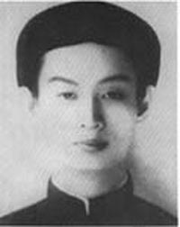 A young slim man aged around 20, with sharp eyes and nose, wearing a cylindrical traditional Vietnamese cloth headpiece and tunic. Both the headpiece and tunic are black.