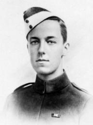 A head and shoulders portrait of a young man with dark hair in military uniform. He is wearing a cap tilted on one side of his head, and has a medal ribbon on his breast.
