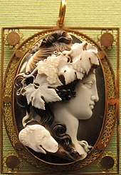 Brown and white stone cameo of a woman facing right with flowers and leaves in her hair