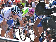 Photograph of three sprinting cyclists with a crowd watching in the background