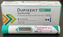 Photo of a Dupixent (dupilumab) 300mg/2mL auto-injector pen and accompanying packaging. The pen is labeled in Japanese.