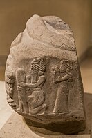 A God putting a foundation nail in the ground, protected by a Lama goddess, in front of a roaring lion. Coiled snake on top. Inscriptions in Linear Elamite and Akkadian. Time of Puzur-Inshushinak, circa 2100 BC, Louvre Museum.[27]