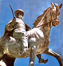 A metal statue of a turbaned, bearded man, sword in hand, riding a horse