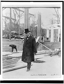 Black-and-white photograph of Brewer walking past a construction site