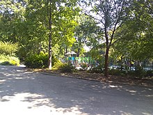 Pathway on the left with a playground seen through a group of trees