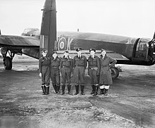 Black and white photo of six men standing behind an aircraft