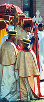 Ethiopian Orthodox clergy lead a procession in celebration of Saint Michael. During such processions, the clergy carry Ethiopian processional crosses and ornately covered tabots around the church building's exterior (Garland, Texas)