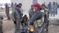 Fighters of the Tell Abyad Revolutionaries Brigade and the YPG warm themselves at a campfire.