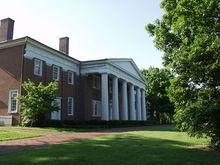 A brick building with white accents and six white columns