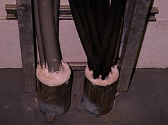 Electrical cable through-penetration, firestopped by an intumescent sealant, to restore the two-hour fire-resistance rating of the concrete floor.