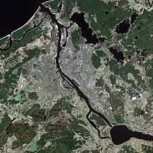 Satellitenaufnahme von einer Stadt mit Fluss und Seen. Die bebauten Gebiete und Landflächen sind gut zu erkennen.