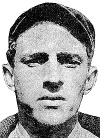 A black and white photograph of a man in a sweater and baseball cap