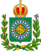 Coat of arms consisting of a shield with a green field with a golden armillary sphere superimposed on the red and white Cross of the Order of Christ, surrounded by a blue band with 19 silver stars; the bearers are two arms of a wreath, with a coffee branch on the left and a flowering tobacco branch on the right; and above the shield is an arched golden and jewelled crown