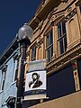 A banner remembers John Hunt Morgan's role in the history of Elizabethtown, KY. A Confederate cannonball is embedded in the blue building at left (the ball is visible just below and to the left of the nearest second-story window).