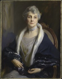 An oil portrait of a white woman with grey hair, seated, dressed in greys and dark blue