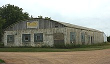 Photo of an old factory building with a fading sign that reads "Colby Cheese Factory"