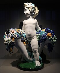 Secessionist putto with two cornucopias with floral cascades, very similar to the ones found in a lot of Art Deco of the 1910s and 1920s, by Michael Powolny, designed in c. 1907, produced in 1912, ceramic, Kunstgewerbemuseum Berlin[232]