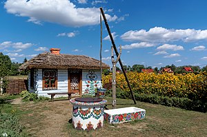 A cottage and a well in the village of Zalipie, painted in a traditional floral motif
