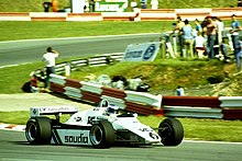 Sideview of a white Williams racing car going through a corner during a race
