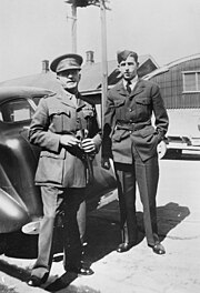 a male in Australian army dress uniform with medal ribbons and a male in Royal Australian Air Force uniform standing at the back of a car