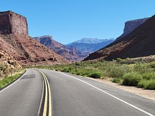Highway through a sandstone gorge, with the Colorado River (not visible) next to the right side of the road.