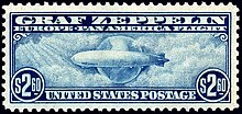 A rectangular postage stamp, torn from a perforated sheet. It is in landscape format and is printed with blue ink on a white background. At the top it says "Graf Zeppelin: Pan-American Flight" and on the bottom "$2.60 United States Postage $2.60". In between is a depiction of the airship, flying from right to left, against a background of the planet Earth. Stylised clouds swim across the scene, and rays of sunlight are shining in from the top-left corner.
