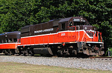 A Providence and Worcester Railroad locomotive parked on a track. It is numbered 2009, and is connected to a passenger car wearing the same paint scheme.