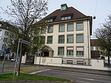 Thiersteiner-Schulhaus mit Turnhalle, Bärschwilerstrasse 11, Basel. Erbaut 1914 bis 1915 von Theodor Hünerwadel (1864–1956), Architekt und Hochbauinspektor. Jean Tinguely (1925–1991) besuchte die Primar- und Realschule im «Thierschteli».