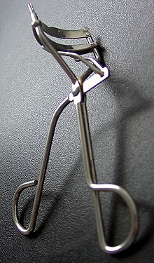 The picture shows a metal eyelash curler laying on its side