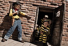 A girl dressed as Lucky Luke points a revolver at other children dressed as The Daltons.
