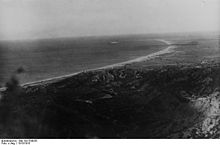 A black and white photograph of a beach taken from an elevated position.