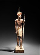 A guardian statue wearing the red crown which reflected the facial features of the reigning king, probably Amenemhat II or Senwosret II, and which functioned as a divine guardian for the imiut; made of cedar wood and plaster c. 1919–1885 BC