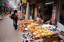 A female customer browsing a fruit shop. Banana and grapes are displayed on the front.