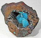 In an open pocket in a matrix of limonite there is a cluster of deep robin's-egg blue chrysocolla with a covering of drusy quartz