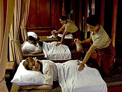 Two masseurs massaging their clients using stretching.
