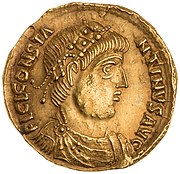 A gold coin showing the profile of a man with beads in his hair