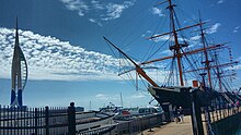 A view of the port side of HMS Warrior alongside Portsmouth Harbour. The Spinnaker Tower can be seen to the far left.