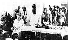 A seated Ida Scudder and Mahatma Gandhi, with other men