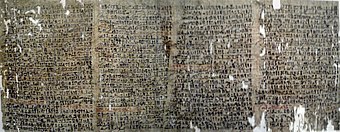 Image of a dark papyrus covered with writings in black ink and scattered holes