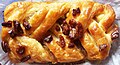 A Danish pastry topped with pecans and maple syrup
