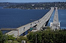 View of two bridges carrying a divided highway over a lake with light traffic