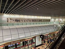 The artwork in the background, with an open view of the platforms one level below, taken from the concourse level