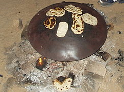 Pita being baked on a convex saj