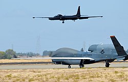 An RQ-4 Global Hawk taxies on the flight-line as a U-2 Dragon Lady makes its final approach at Beale Air Force Base during 2013.