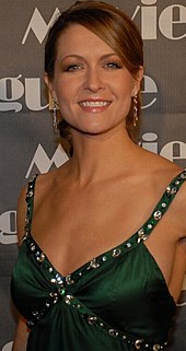 A brown-haired woman in her thirties wearing a green dress.