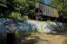 Coal car sitting above a mural depicting various 18th- and 19th-century artists, as well as the text, “We are all different flowers from the same garden”