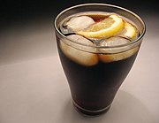 A glass of cola served with ice cubes and lemon